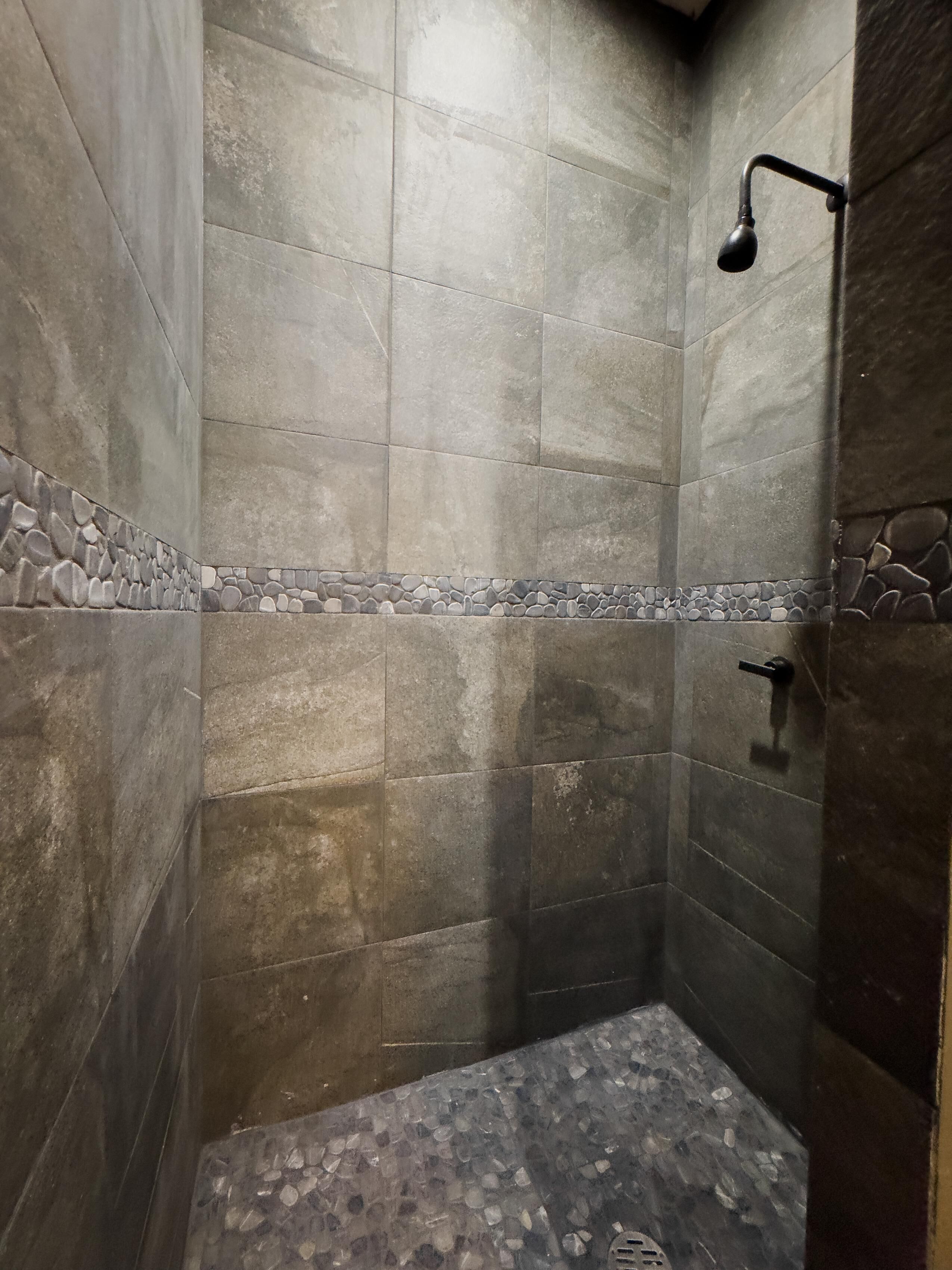 Eine Dusche mit Steinfliesen und einer Duschbrause.