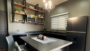 A modern kitchen with a central island, built-in appliances, and a pendant light. - Modern 2‑Bed Condo in Golden Zone: Walk Everywhere! (Mazatlan)