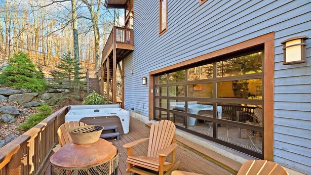 Una terraza de madera con mobiliario exterior, un hogar y un jacuzzi.