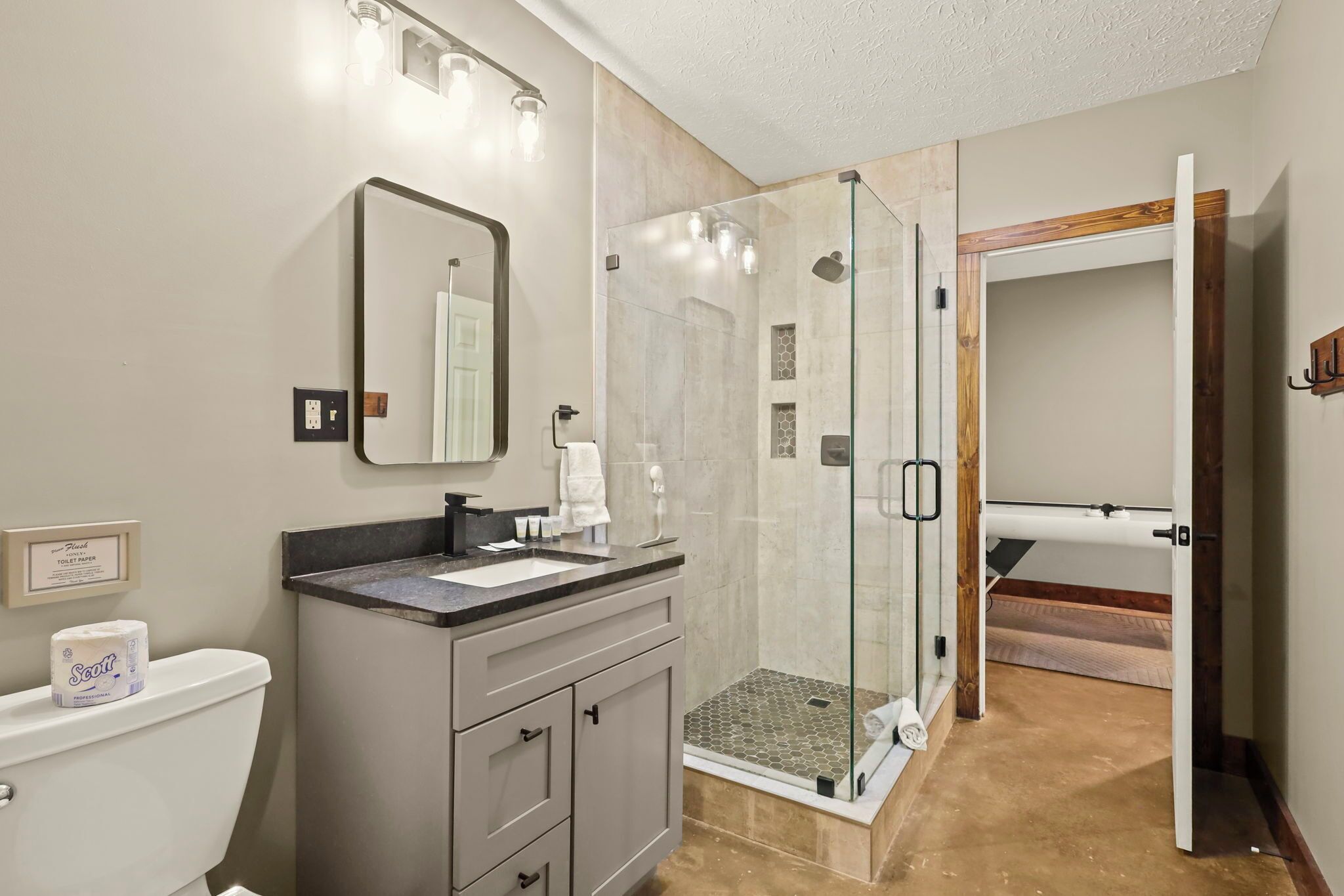Une salle de bain avec une douche à parois de verre, un lavabo avec un miroir et des toilettes.