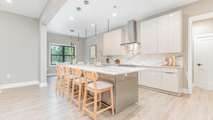 A modern kitchen with a large island, bar stools, and pendant lighting. - Ultimate Lake Norman Getaway - 6BR, Pool, hot tub, Fire Pit, Kayaks, & Boat Dock (Mooresville)
