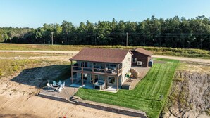 A large house with a spacious porch, a well-maintained lawn, and a beach area with kayaks.
