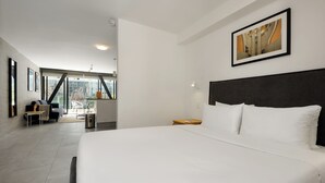 Une chambre d’hôtel moderne avec un grand lit, une tête de lit sombre et un tableau encadré au mur.