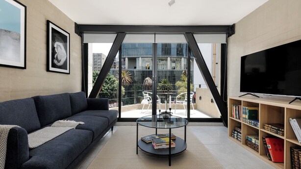 Un salon moderne avec un canapé, une table basse sur laquelle sont posés des livres, un téléviseur et une bibliothèque.