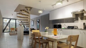 Une cuisine moderne avec un îlot central, des chaises en bois et un escalier en colimaçon.