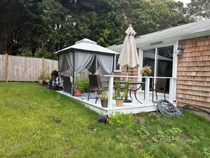 Un jardin avec un patio couvert, du mobilier d’extérieur et des plantes en pot.