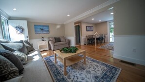 A spacious living room with a sofa, coffee table, and a dining area with chairs and a table.
