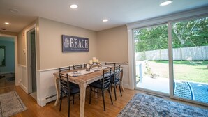 A dining area with a wooden table, six chairs, and a 'BEACH' sign on the wall.