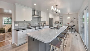 A modern kitchen with a large island, stainless steel appliances, and a dining area with bar stools. - Luxury 6-Sleeper: Pool, HotTub, 8 mins to Sonoma Square, and Deluxe Coffee Bar! (Sonoma)