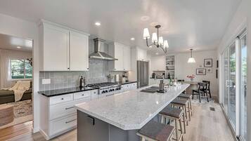 A modern kitchen with a large island, stainless steel appliances, and a dining area with bar stools.