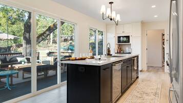 Cocina moderna con una isla grande, puertas de vidrio correderas que dan a un patio exterior y un microondas empotrado.