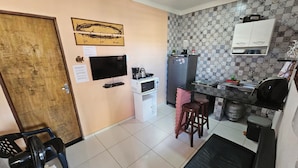 A compact kitchen with a refrigerator, microwave, and a small bar area.