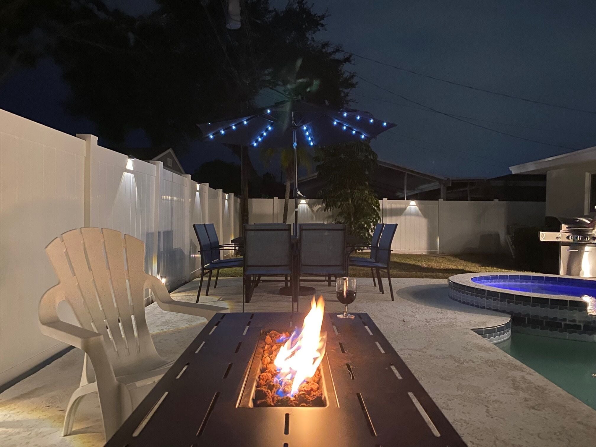 An outdoor patio with a fire pit, chairs, and a pool.