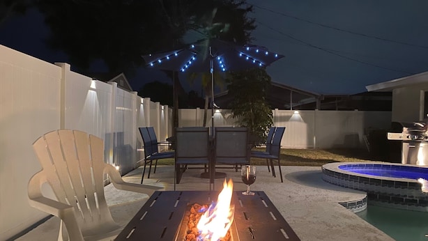 Une terrasse extérieure avec un foyer, des chaises et une piscine.