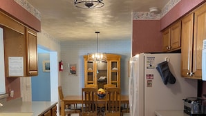 Une cuisine avec des meubles de rangement en bois, une table à manger avec des chaises, un réfrigérateur et une cuisinière.