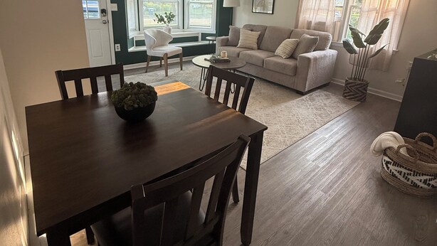 A dining area with a wooden table and chairs, a sofa set, and a window with curtains. - Cozy Cottage 1.5 mile to  Stadium Ann Arbor (Ann Arbor)
