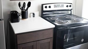 A kitchen with dark wooden cabinets, a black stove, and a white countertop. - Cozy Cottage 1.5 mile to  Stadium Ann Arbor (Ann Arbor)