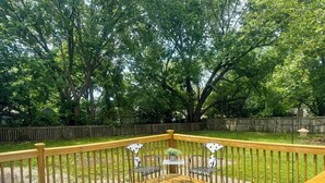 Une terrasse en bois avec une rambarde, une table et deux chaises.
