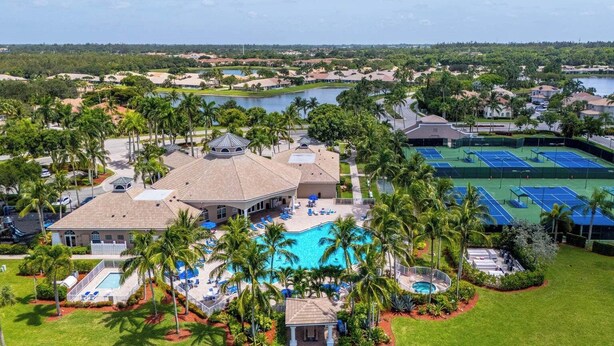 A resort with a large swimming pool, tennis courts, and a view of the surrounding landscape.