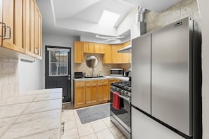 A compact kitchen with wooden cabinets, a stainless steel refrigerator, a gas stove, and a microwave.