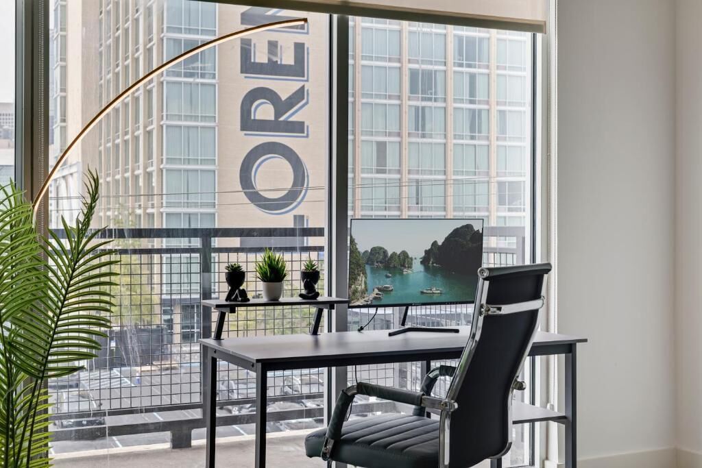 Un espace de bureau moderne doté d’une grande fenêtre donnant sur un paysage urbain et une étendue d’eau.