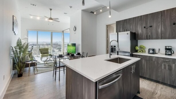 Una cocina moderna con una isla central, armarios de madera oscura y electrodomésticos de acero inoxidable.
