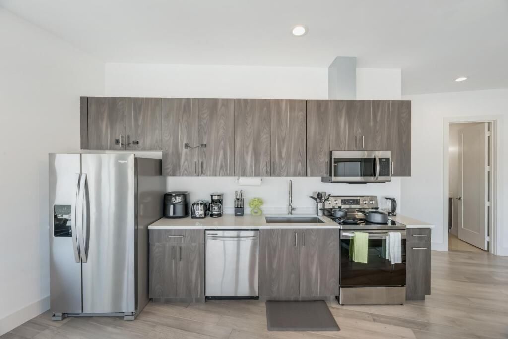 A modern kitchen with a refrigerator, microwave, coffee maker, and dishwasher.