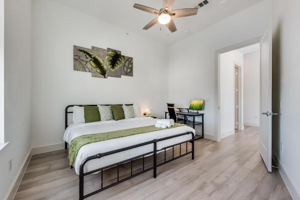 A bedroom with a bed, a desk, and a ceiling fan.