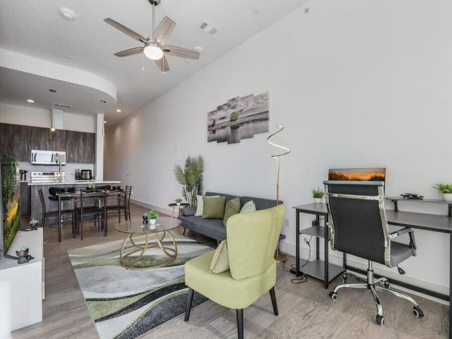 A modern living room with a sofa, a dining area, and a kitchen in the background.