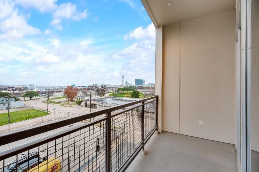 A balcony with a metal railing overlooking a cityscape.