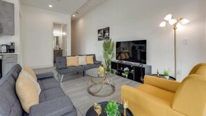 Una sala de estar moderna con un sofá modular, una mesa de centro redonda y un televisor.