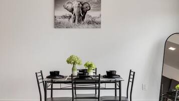A dining area with a table set for four, featuring black chairs and a black tablecloth. There are two vases with green flowers on the table.