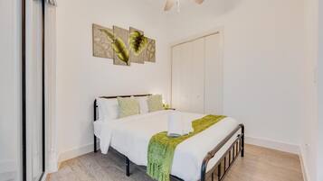 Un dormitorio con cama, ventilador de techo y obras de arte en la pared.