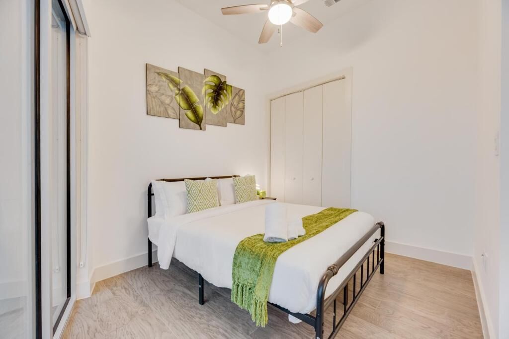 A bedroom with a bed, a ceiling fan, and artwork on the wall.