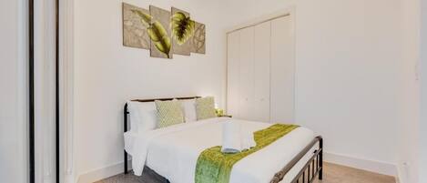 A bedroom with a bed, a ceiling fan, and artwork on the wall.