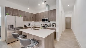 Una cocina moderna con una isla central, electrodomésticos de acero inoxidable y un diseño minimalista.