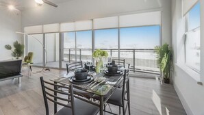 Un comedor moderno con una mesa preparada para dos personas, ventanas grandes y un ventilador de techo.