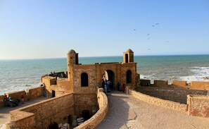 Una fortificación de piedra con portales y torres de arco que dominan el mar.