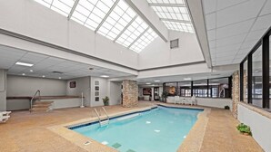 Una piscina interior con un pilar de piedra, una escalera y vistas del cielo a través del techo.