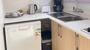 Een kleine keuken met een magnetron, broodrooster, koffiezetapparaat, spoelbak en vaatwasser.