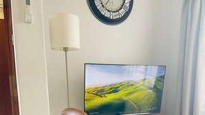 Een moderne woonkamer met een flatscreen televisie, een bruine leren fauteuil, een ronde houten salontafel en een decoratieve glazen bol.