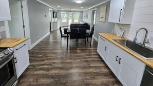 Una cocina moderna con armarios blancos, encimera de madera y pileta de acero inoxidable.