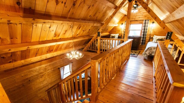 A wooden cabin with a loft bedroom, a staircase, and a chandelier. - Log Cabin Near Bangor and Acadia National Park (Winterport)