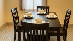 A dining area with a table set for four, four chairs, a hanging light fixture, and a window with curtains. - Stay in a centrally located home, 1.5 miles from downtown Ann Arbor. (Ann Arbor)