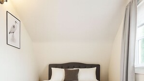 A bedroom with a bed, a wall-mounted light fixture, a framed picture, and a window with curtains. - Stay in a centrally located home, 1.5 miles from downtown Ann Arbor. (Ann Arbor)