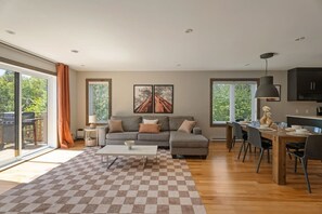 A modern living room with a sofa, coffee table, and dining area.