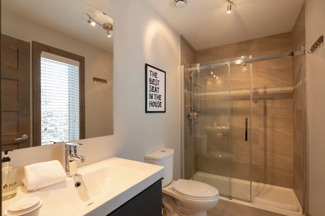 Une salle de bain moderne avec une douche à parois de verre, un lavabo blanc et des toilettes.