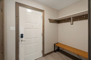 Een kamer met een witte deur, een bankje en een houten plank.