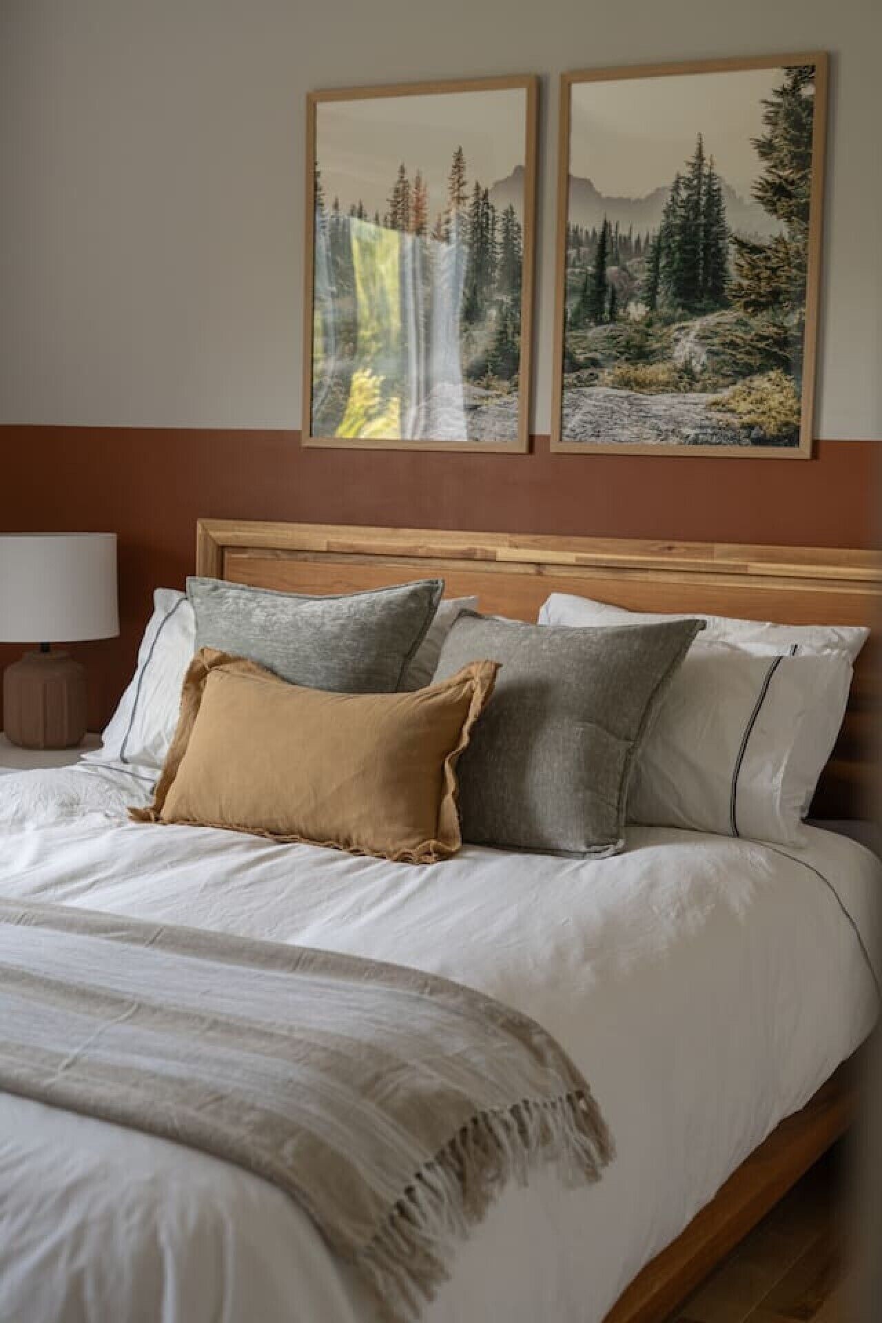 A bed with a wooden headboard, multiple pillows, and a blanket.
