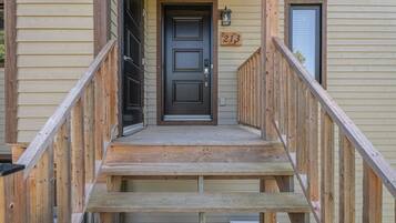A wooden staircase leading to a dark-colored door with the number 213 on the wall.